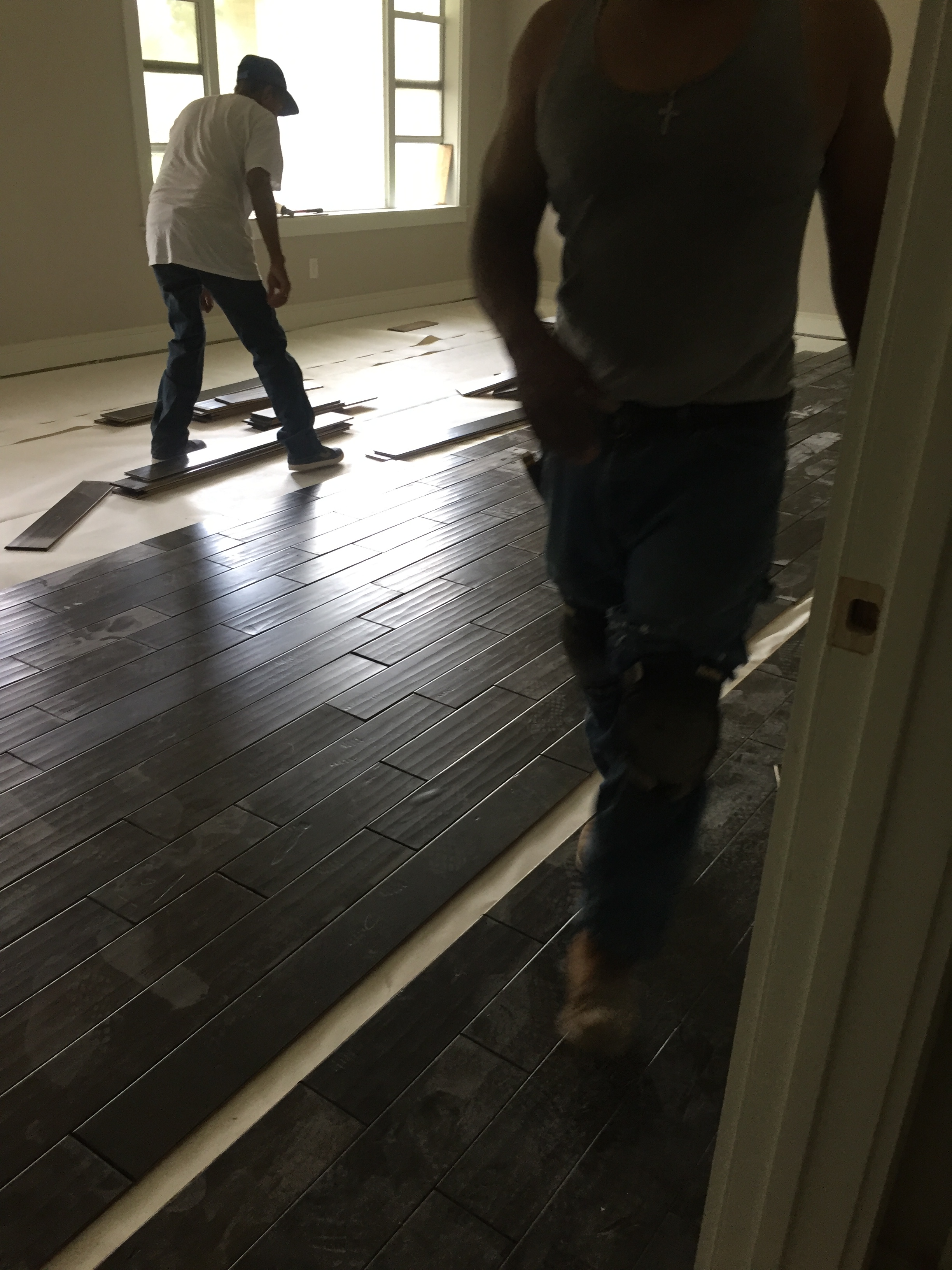 Two men installing vinyl plank flooring